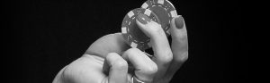 woman's hand holding poker chips in black and white