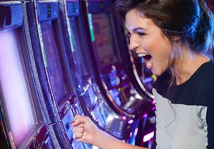 woman yelling in excitement in front of slot machine