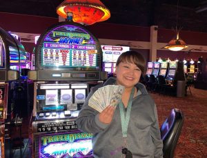 Female holding cash in front of Triple Diamond slot machine